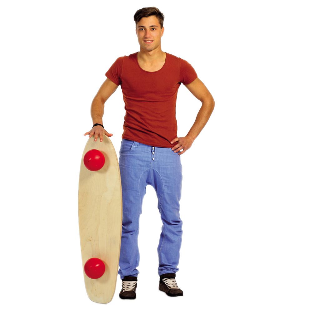 Mann mit Togu Balanza® Freeride. Holzbrett mit roten Kugeln. Steht neben dem Brett, weißer Hintergrund.