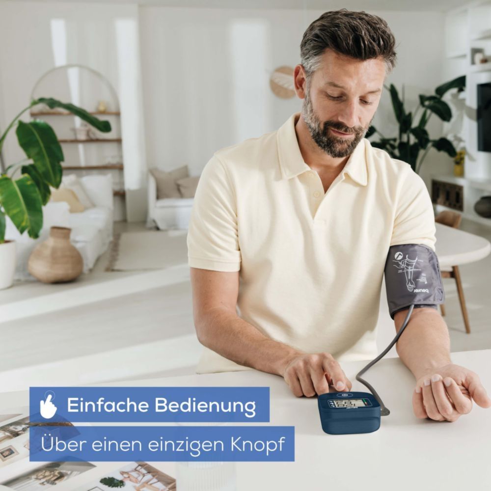 Mann bedient Oberarm-Blutdruckmessgerät mit einem Knopf. Einfache Handhabung.