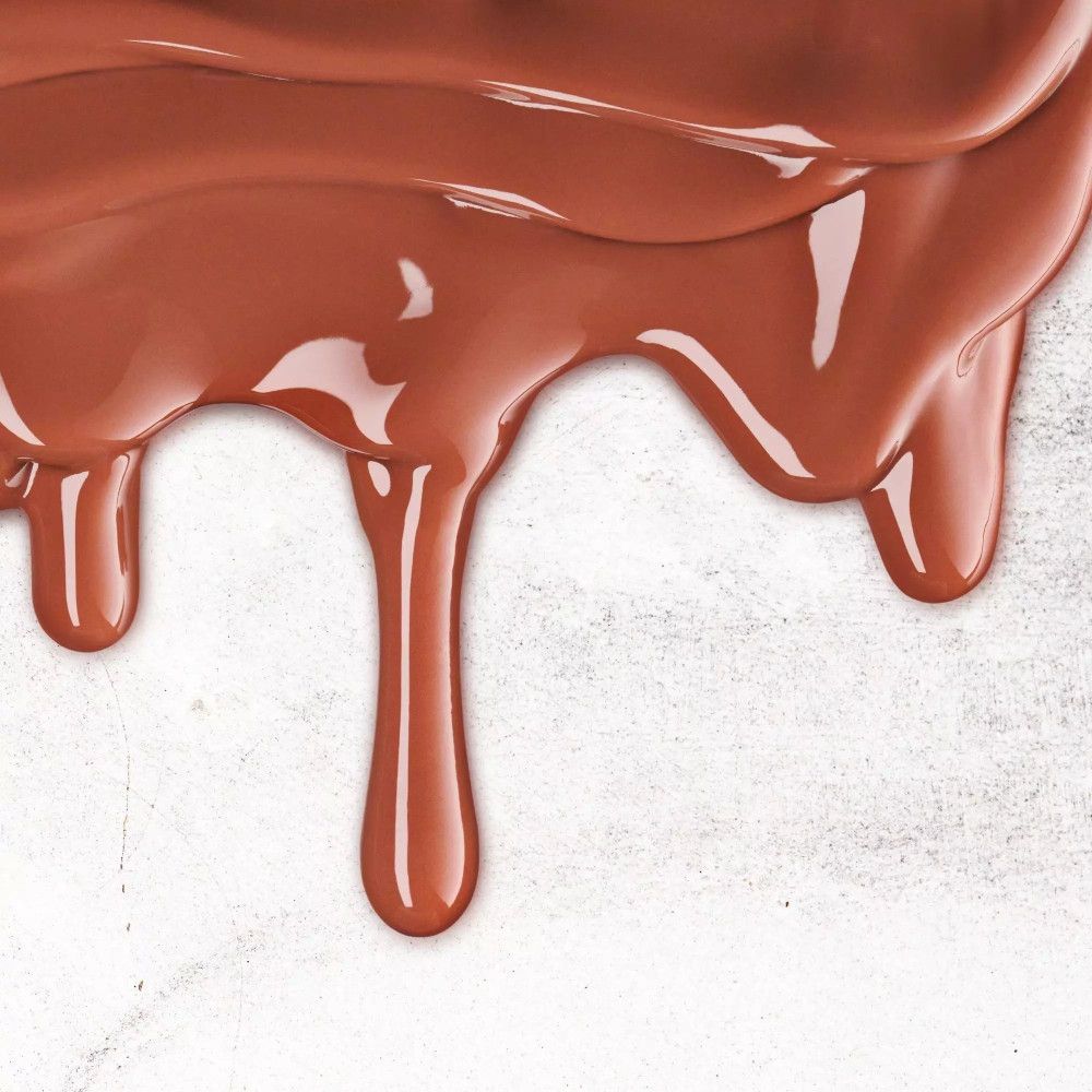 Braune, tropfende Flüssigkeit auf hellem Untergrund. Flüssigkeit tropft von oben nach unten. Helle Oberfläche.