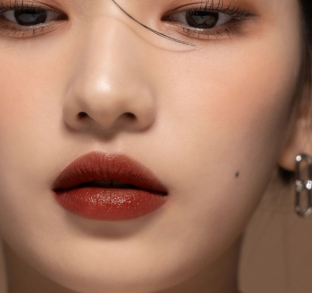 Nahaufnahme von Gesicht mit Lippen, die mit braunem Lipgloss bedeckt sind. Augen und Haut sichtbar.