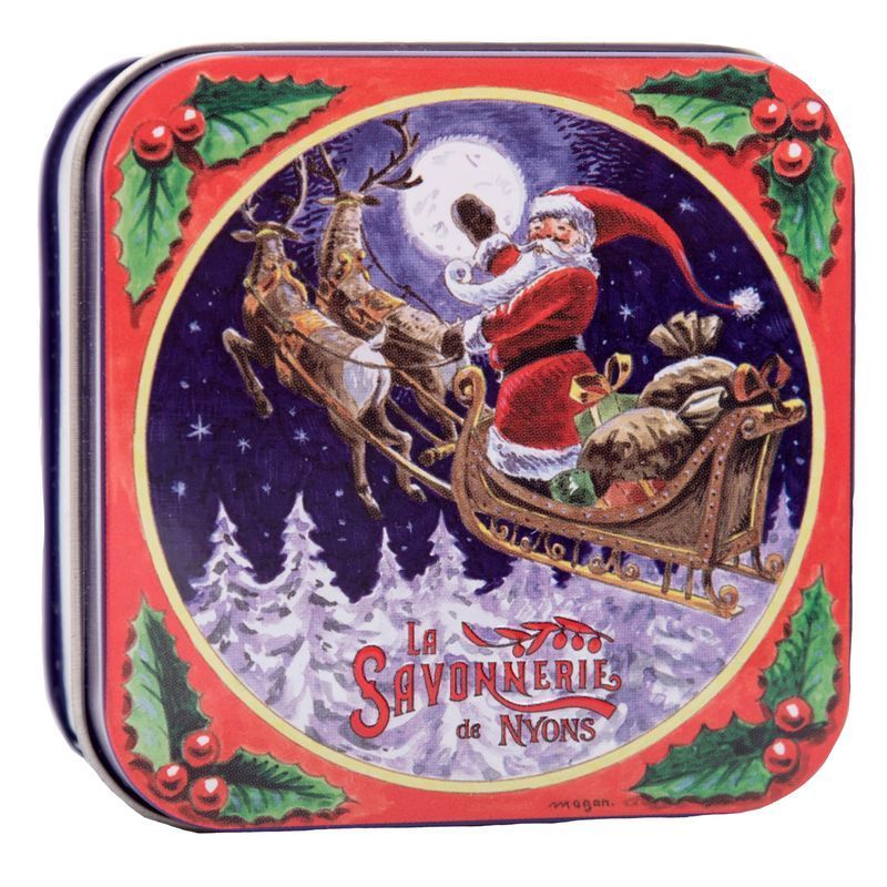 Geschlossene Metallbox. Roter Deckel mit Weihnachtsmotiv: Santa Claus im Schlitten mit Rentieren. Text: La Savonnerie de Nyons. Blaue und weiße Streifen an den Seiten.