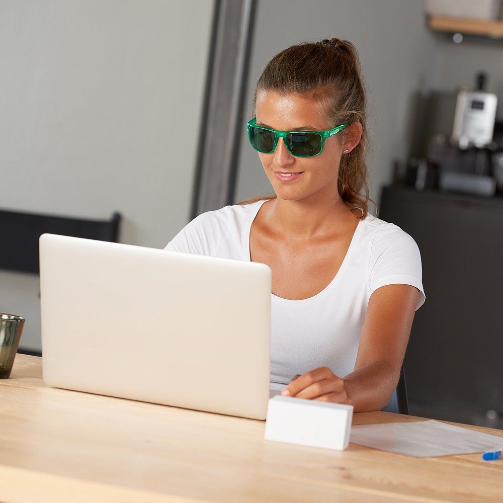 Frau mit grüner Trainingsbrille am Laptop.