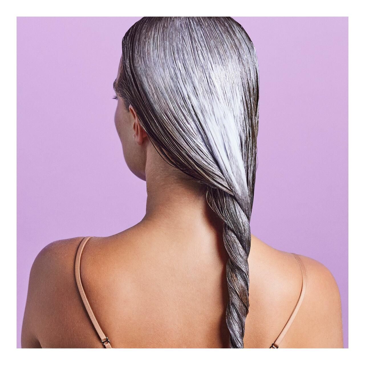 Rückansicht einer Person mit geflochtenem Haar, das mit Conditioner behandelt wurde.