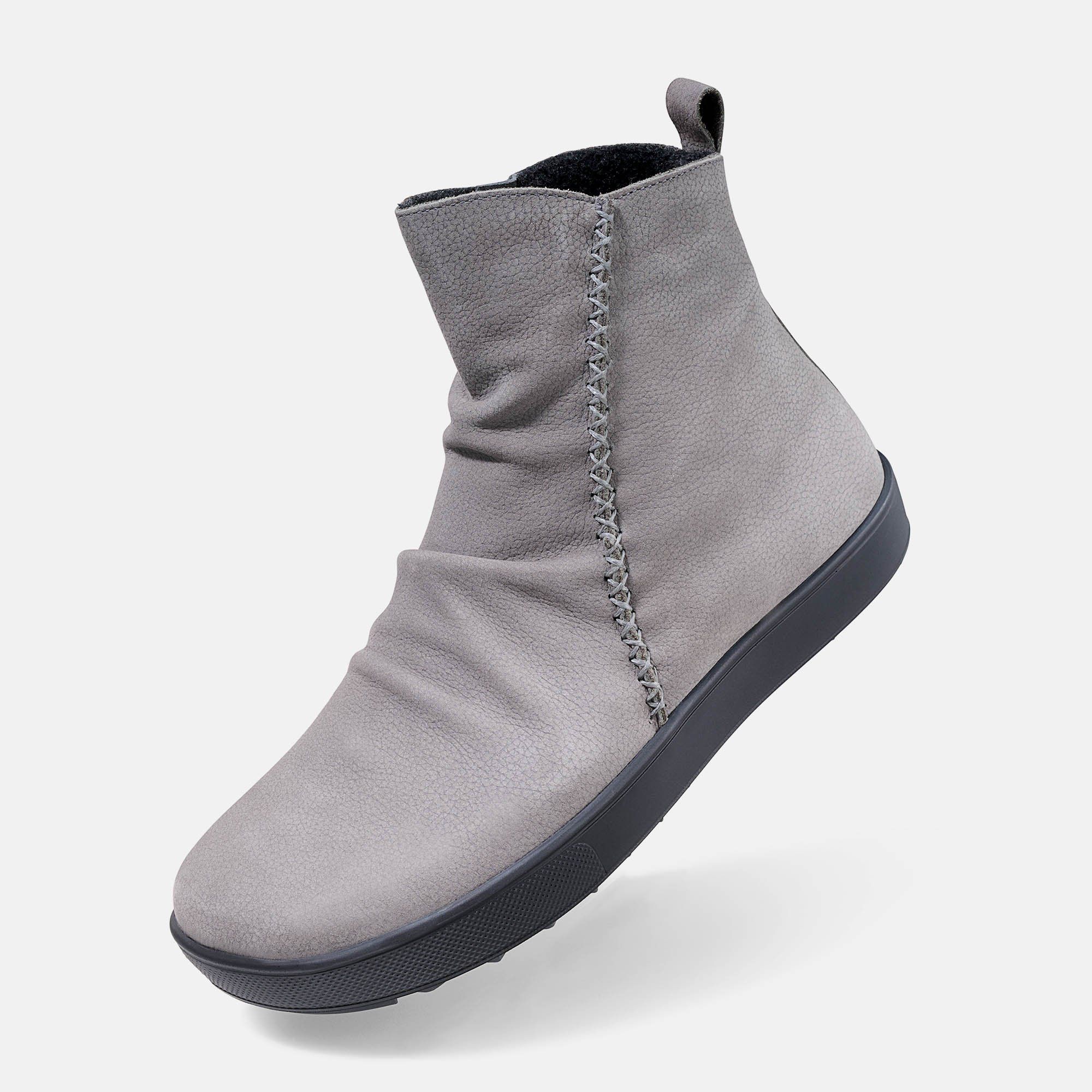 Graue Stiefelette mit breiter Passform. Seitliche Ziernaht, schwarze Sohle. Schuh von der Seite, leicht erhöht.
