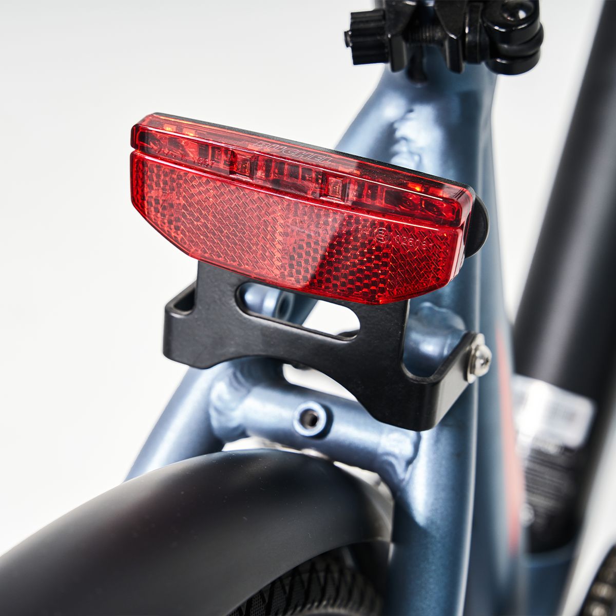 Rotes Rücklicht an einem E-Bike. Schwarze Halterung. Reflektierende Oberfläche.