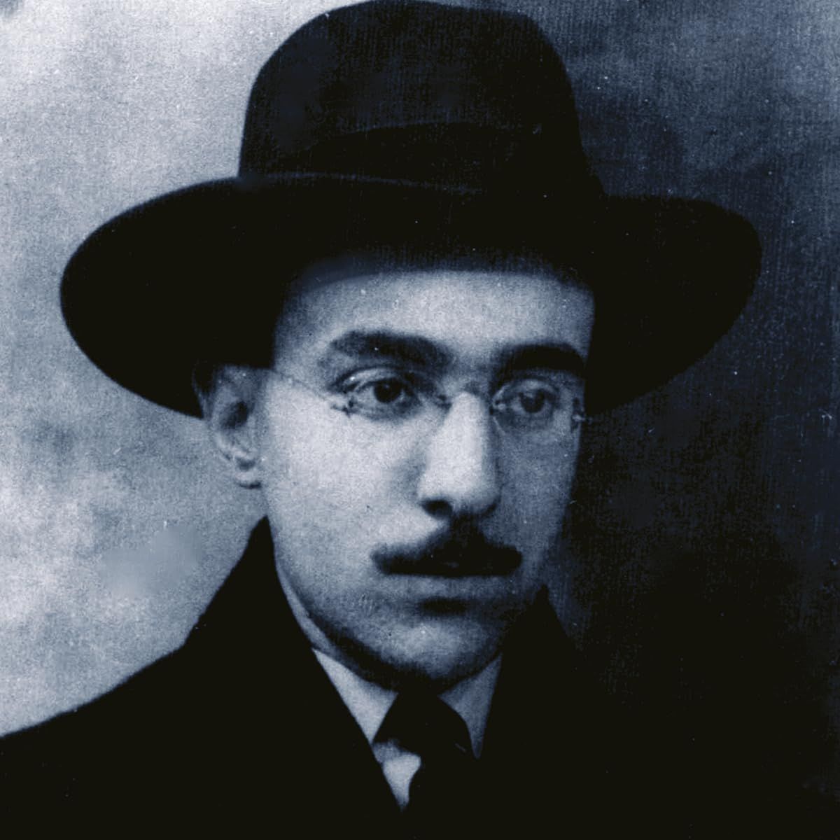 Porträt eines Mannes mit Hut, Brille und Schnurrbart. Schwarz-Weiß-Foto.