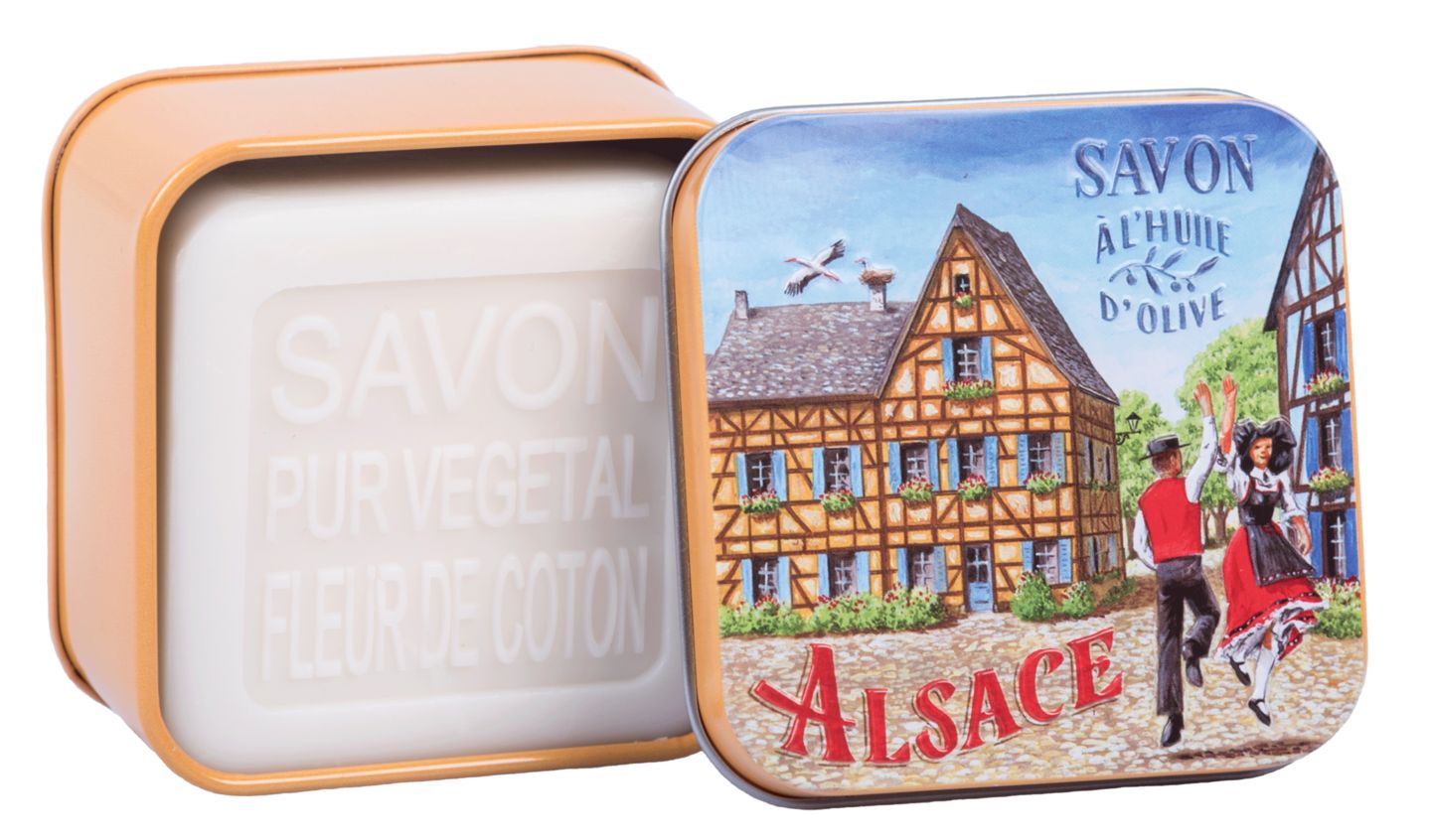 Geöffnete Metallbox mit Seife. Auf dem Deckel: Illustration eines Dorfes. Seife mit Schriftzug "Savon Pur Végétal".