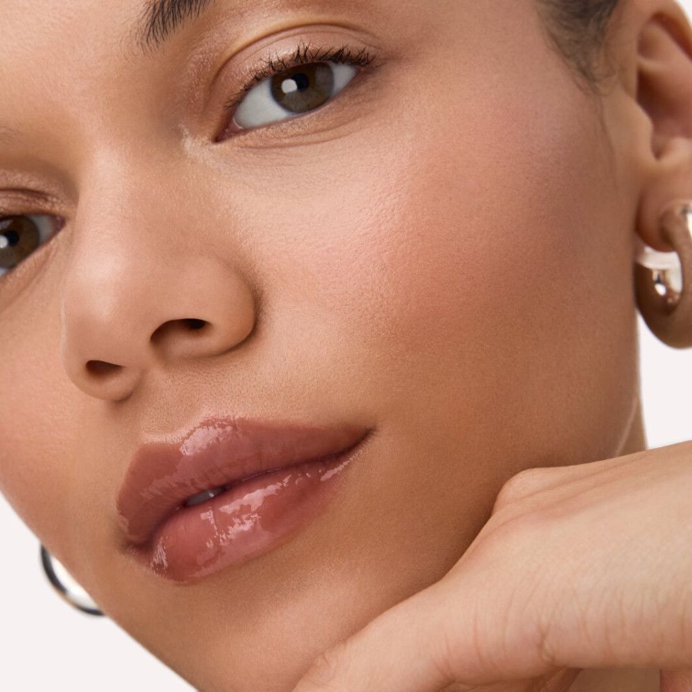 Nahaufnahme eines Gesichts mit glänzendem Lip Balm. Lippen sind rosa und glänzend.