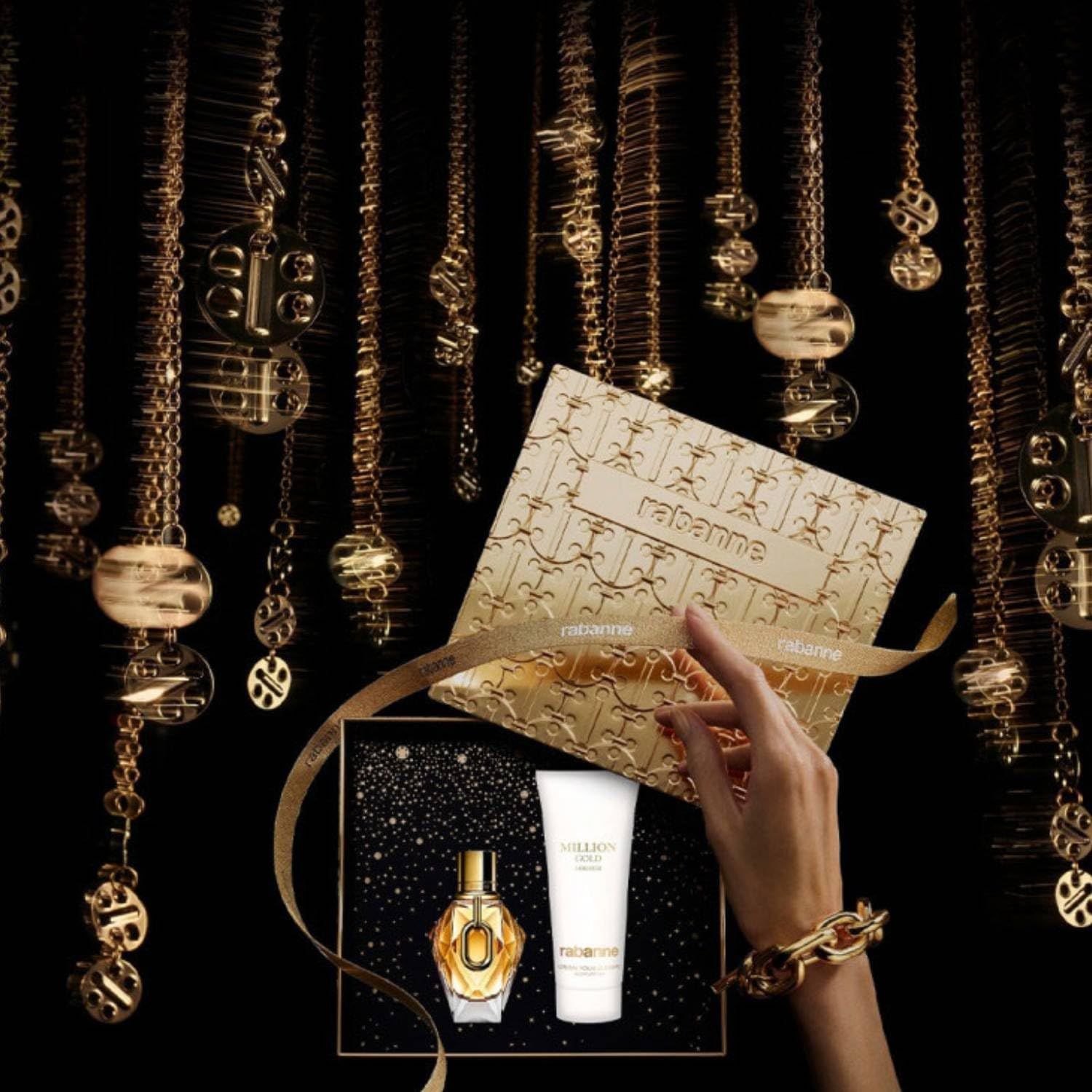 Geschenkbox mit Flakon und Bodylotion. Hand hält die Box. Goldene Dekoration im Hintergrund. Flakon und Lotion sichtbar.