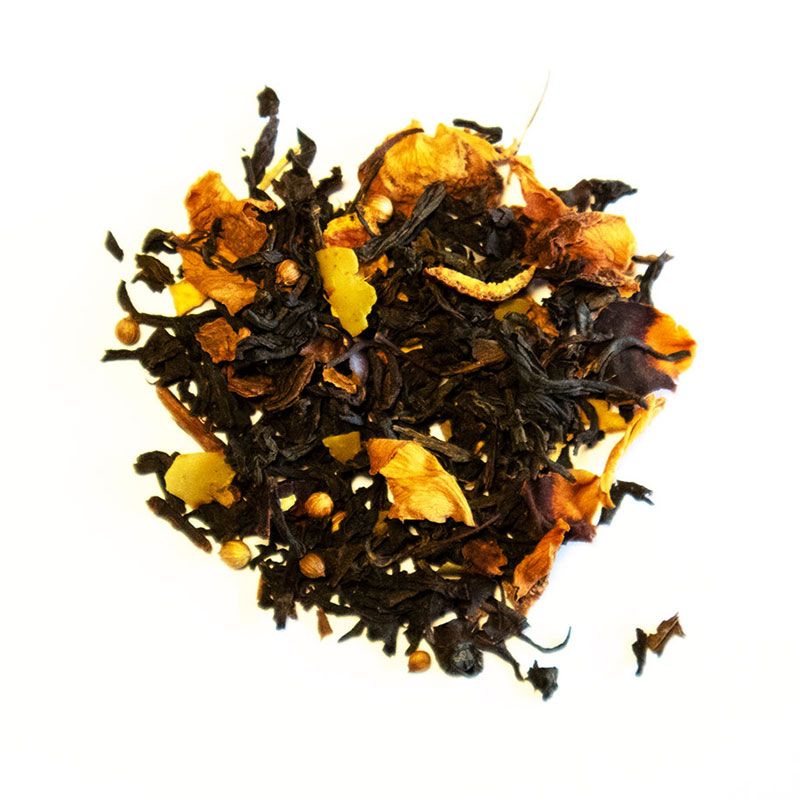 Schwarzer Tee mit getrockneten Früchten und Gewürzen, Draufsicht auf weißem Hintergrund.