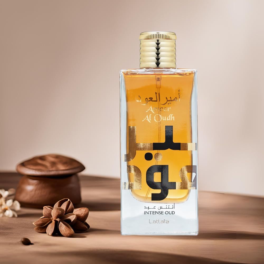 Rechteckige Glasflasche mit goldfarbenem Verschluss. Aufschrift: Ameer Al Oudh Intense Oud. Auf Holzoberfläche.