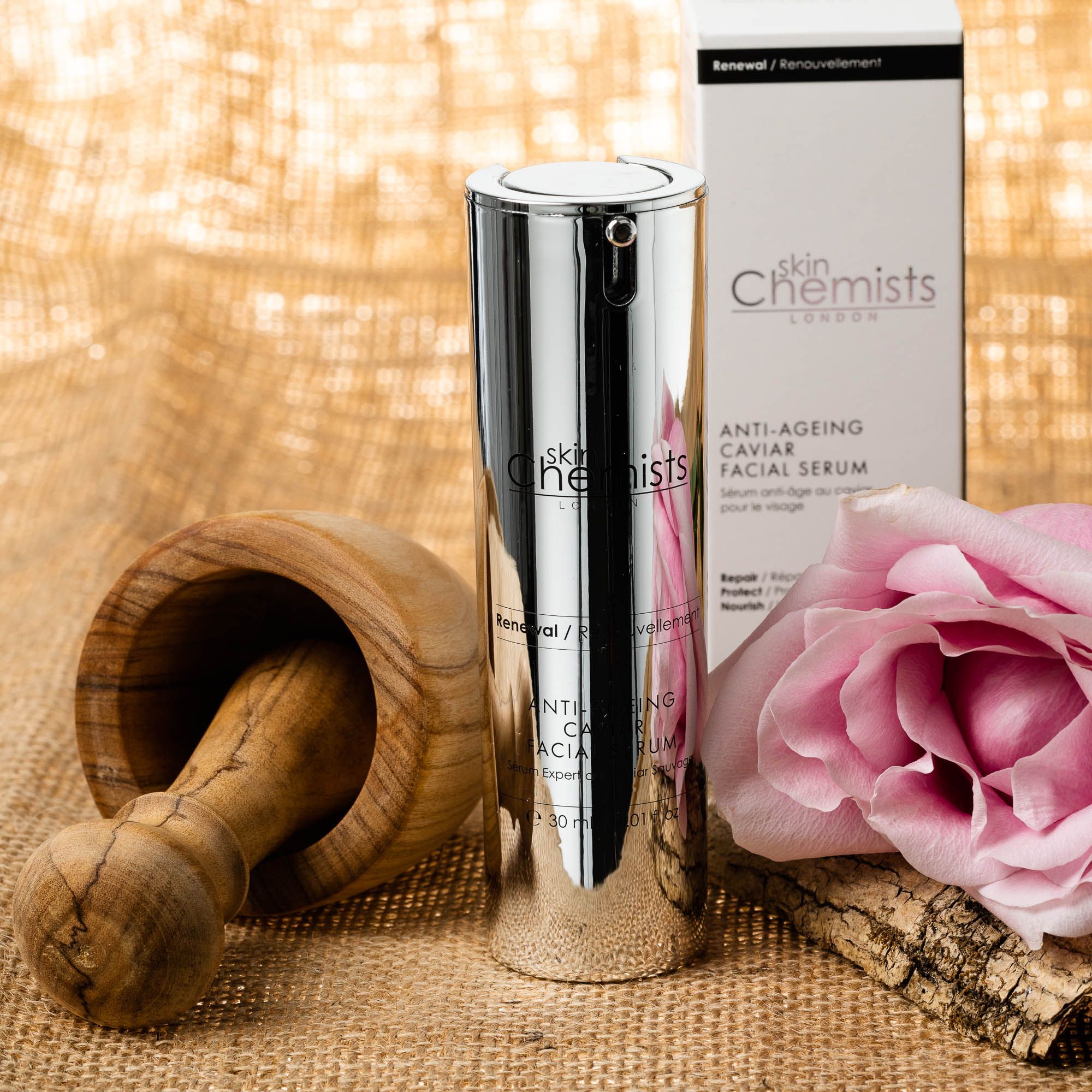 Serumflasche, Mörser, Rose und Schachtel. Flasche silberfarben, Schrift schwarz. Schachtel weiß/schwarz. Beschriftung: skinChemists, Anti-Ageing Caviar Serum.