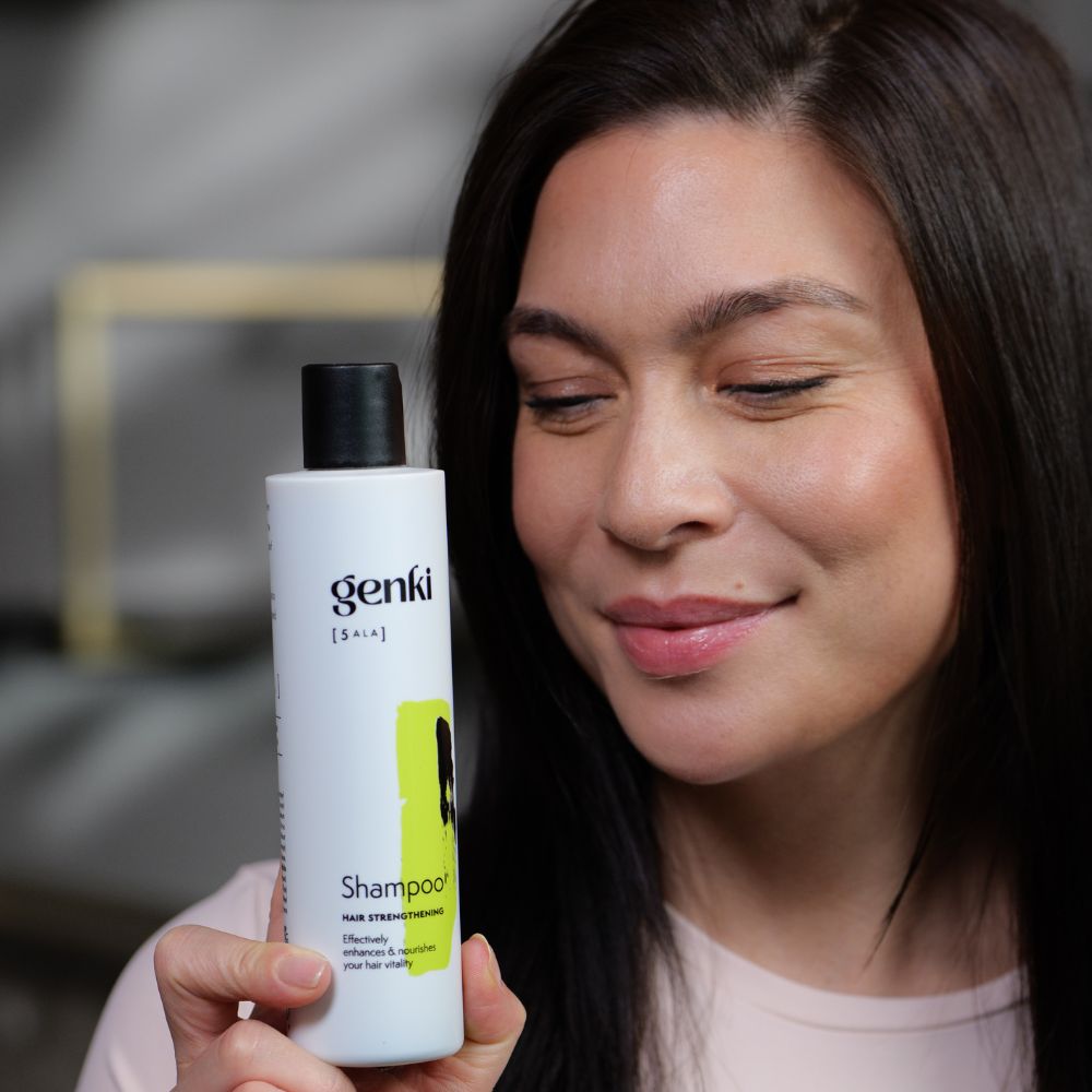Frau hält Shampoo-Flasche. Genki-Logo und Produktbezeichnung sichtbar. Schwarzer Deckel, weißer Flaschenkörper.