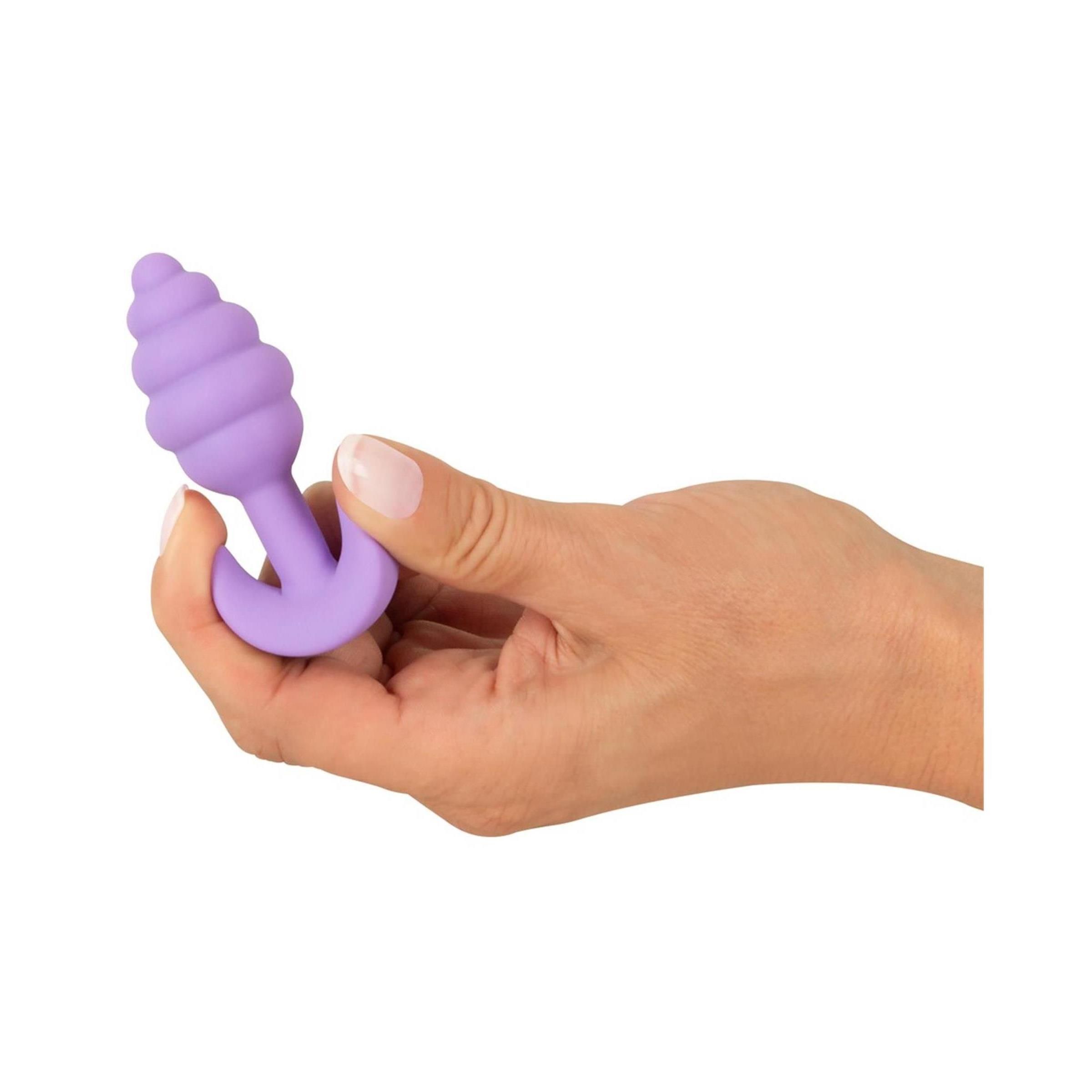 Hand hält lila Analplug mit geriffelter Spitze und T-förmigem Griff.