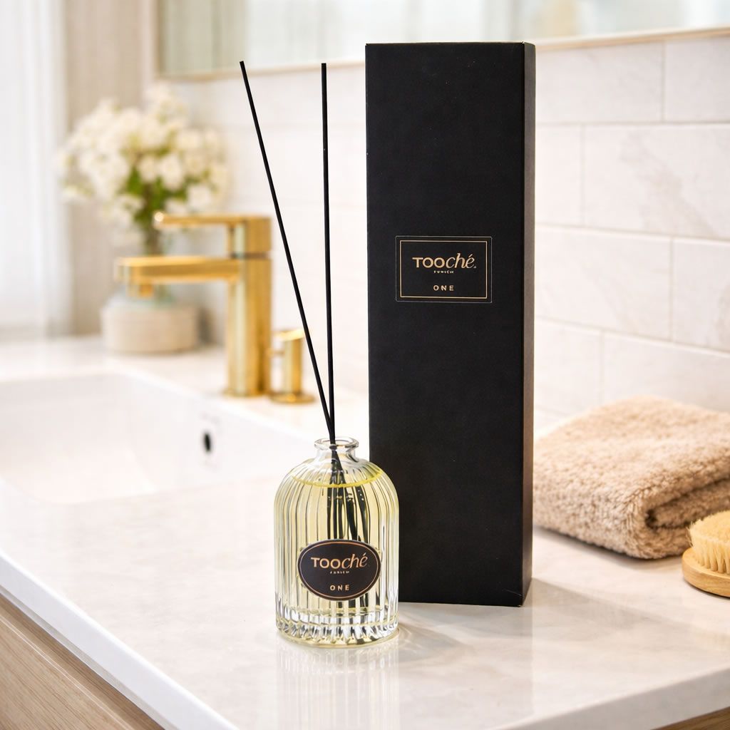 Glasflakon mit Stäbchen und schwarzer Verpackung. Aufschrift: Tooché ONE. Bad-Szene.