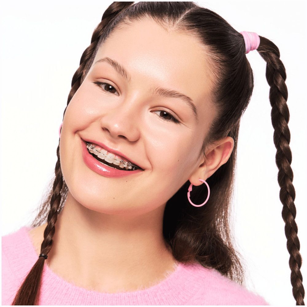 Porträt eines jungen Mädchens mit rosa Ohrringen und Zöpfen. Sie trägt eine Zahnspange.