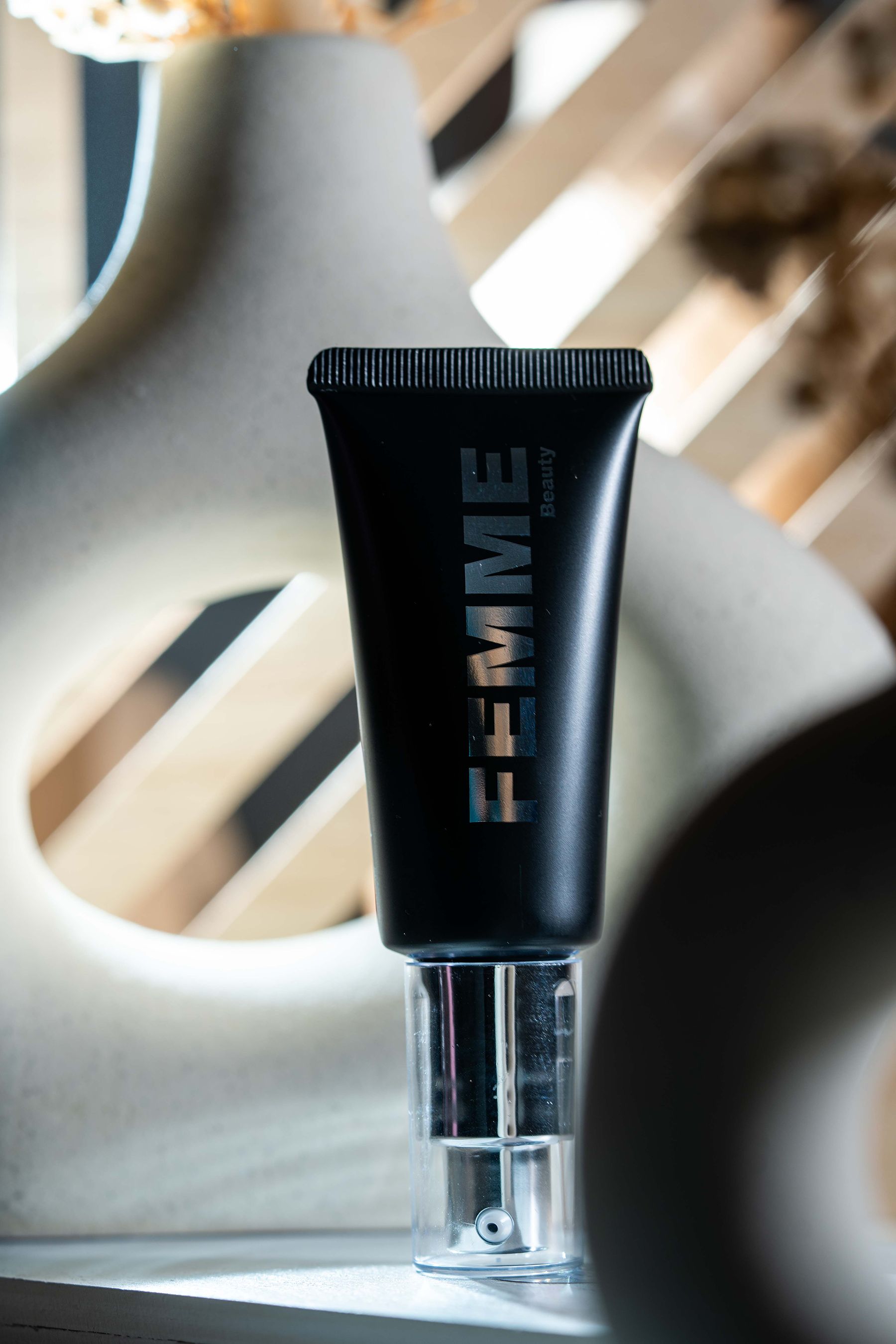 FEMME Intense Hide Concealer in schwarzer Tube mit silbernem Pumpspender, aufrecht stehend.