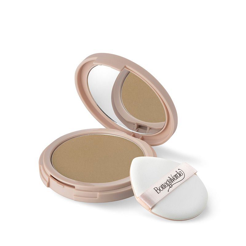 Un fondotinta compatto Bottega Verde d'Amore d'Accordo rosa, con specchio e applicatore. La polvere è marrone chiaro. L'applicatore è bianco con un nastro rosa con il nome del marchio.