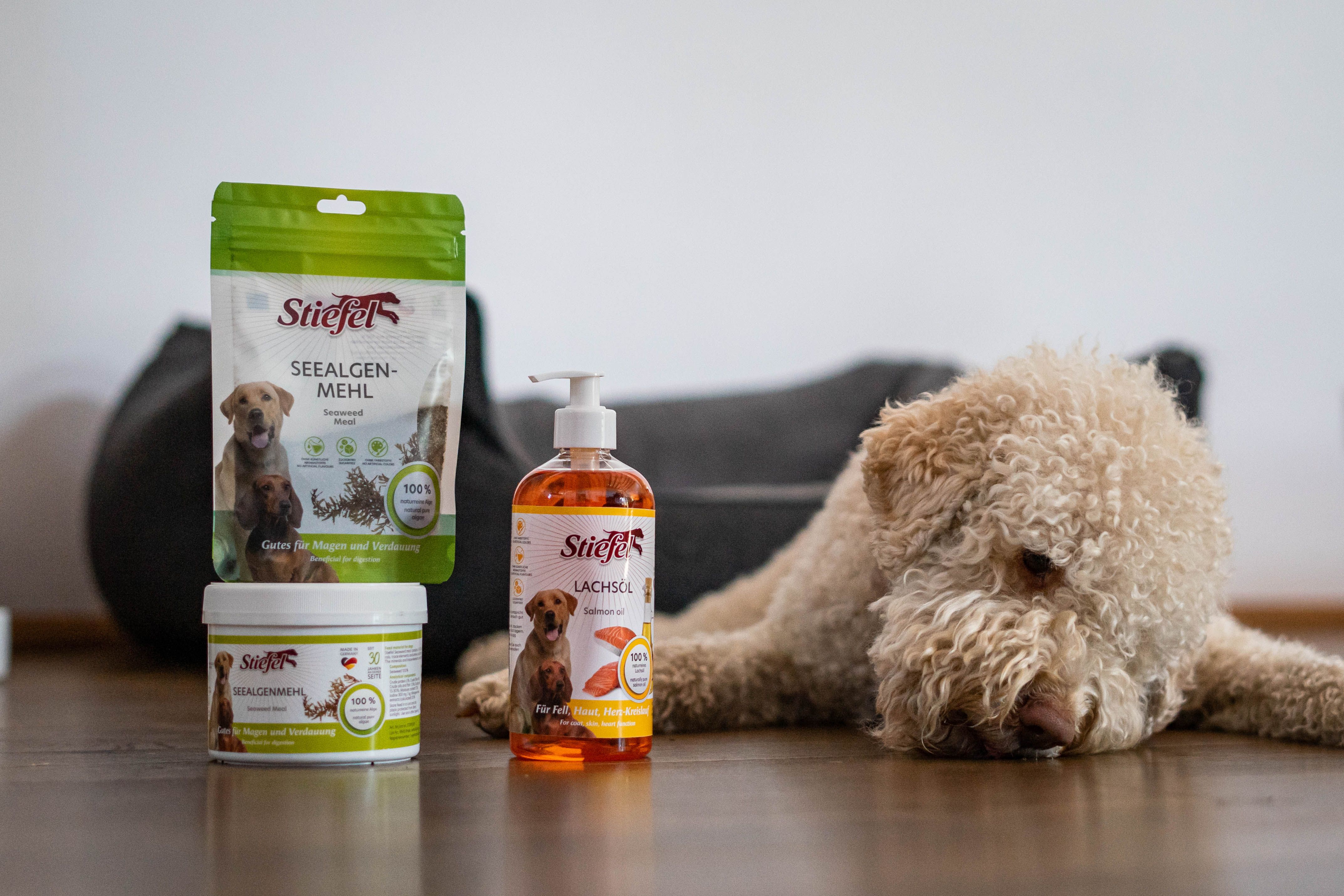 Verschiedene Stiefel-Produkte: Seealgenmehl, Shampoo und Dose. Neben einem Stofftier auf dem Boden.