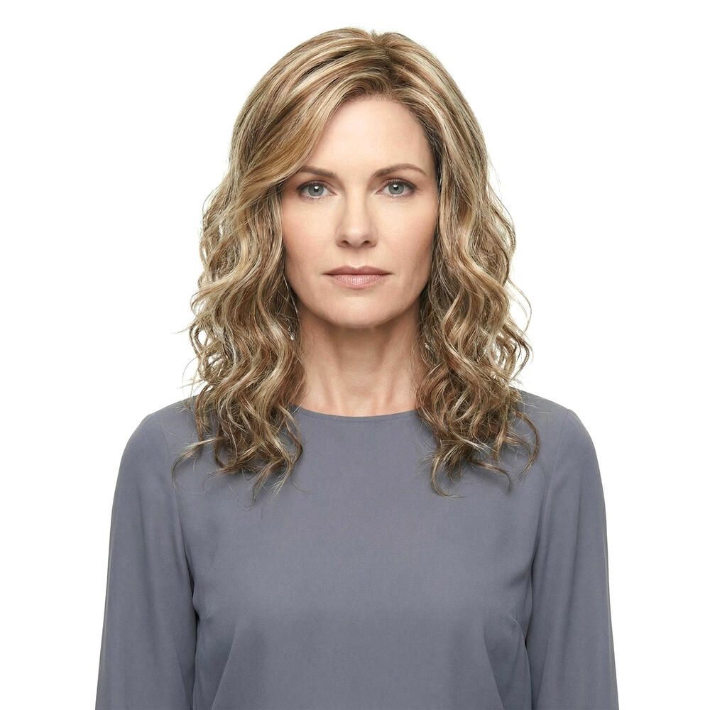 Wellenförmige Perücke mit blonden und braunen Strähnen. Die Frau trägt ein graues Oberteil. Frontansicht.