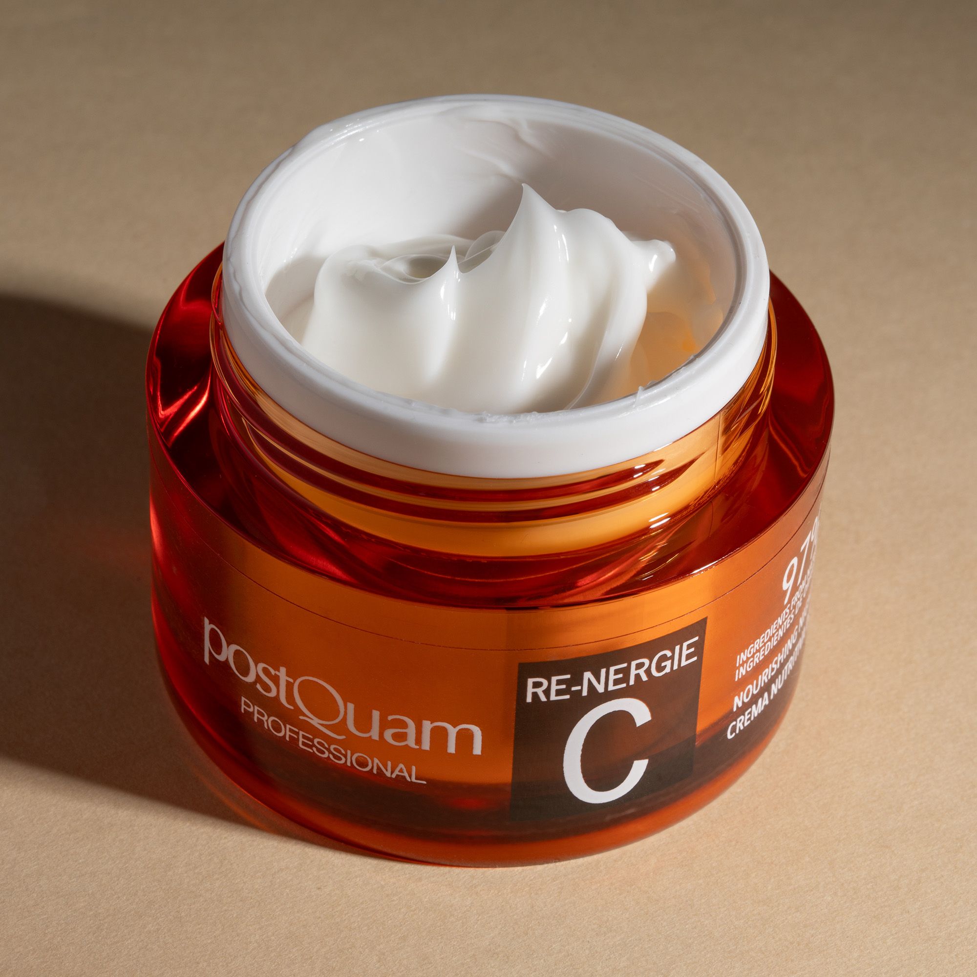 Geöffneter Creme-Tiegel. Aufschrift: PostQuam, Re-Nergie C, 97% Inhaltsstoffe natürlichen Ursprungs. Creme sichtbar.