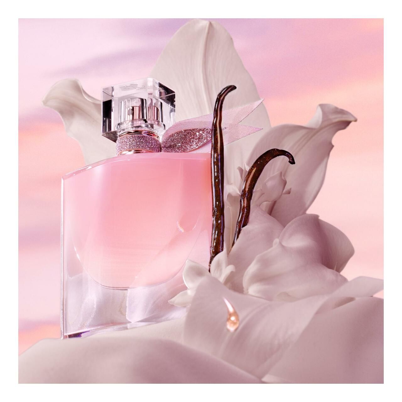Lancôme La vie est belle Vanille Nude Eau de Parfum Flakon umgeben von Blütenblättern und Vanilleschoten.