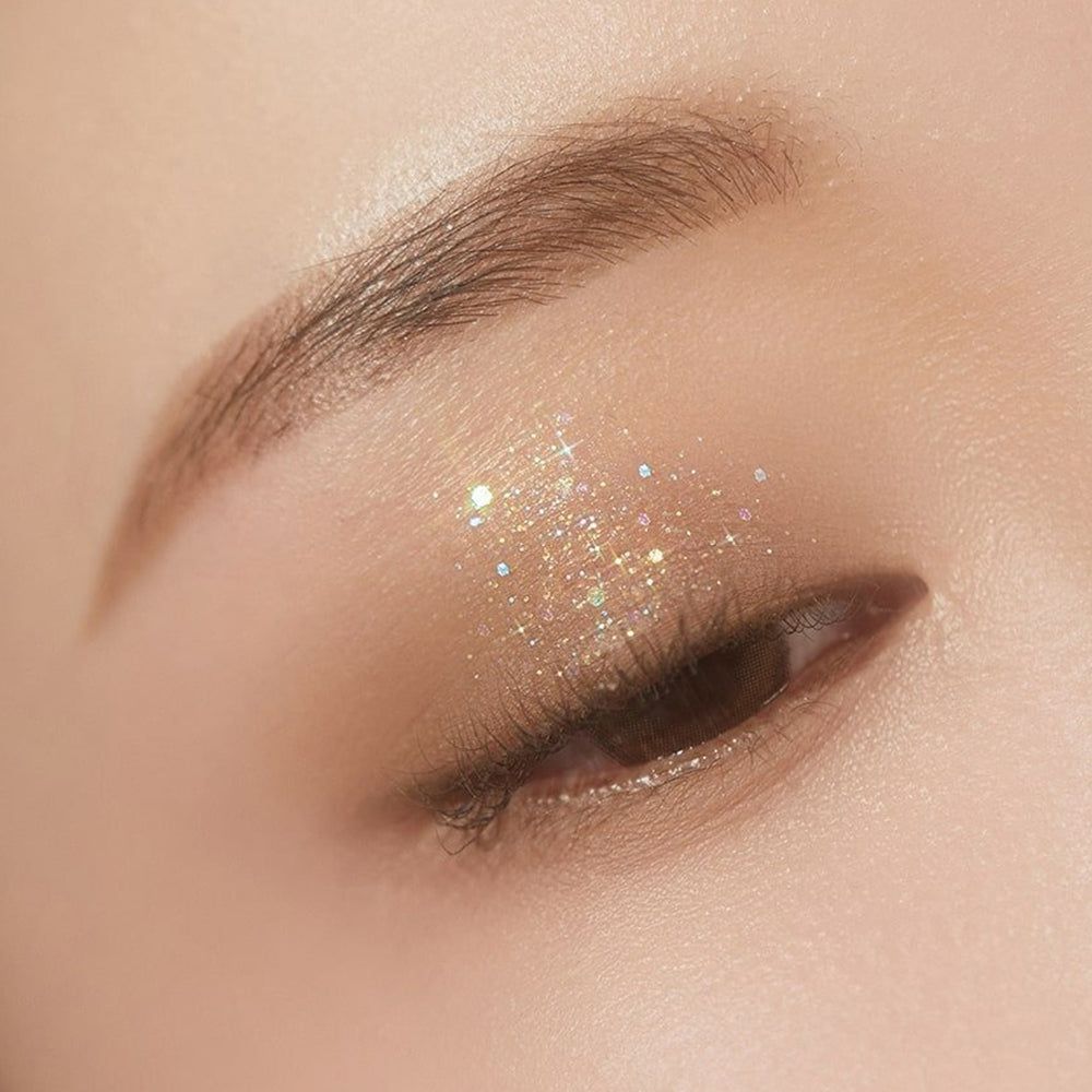 Ein geschlossenes Auge mit schimmerndem Lidschatten und Glitzerpartikeln.