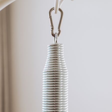 Nahaufnahme einer Metallfeder mit Karabinerhaken. Die Feder ist spiralförmig gewickelt.