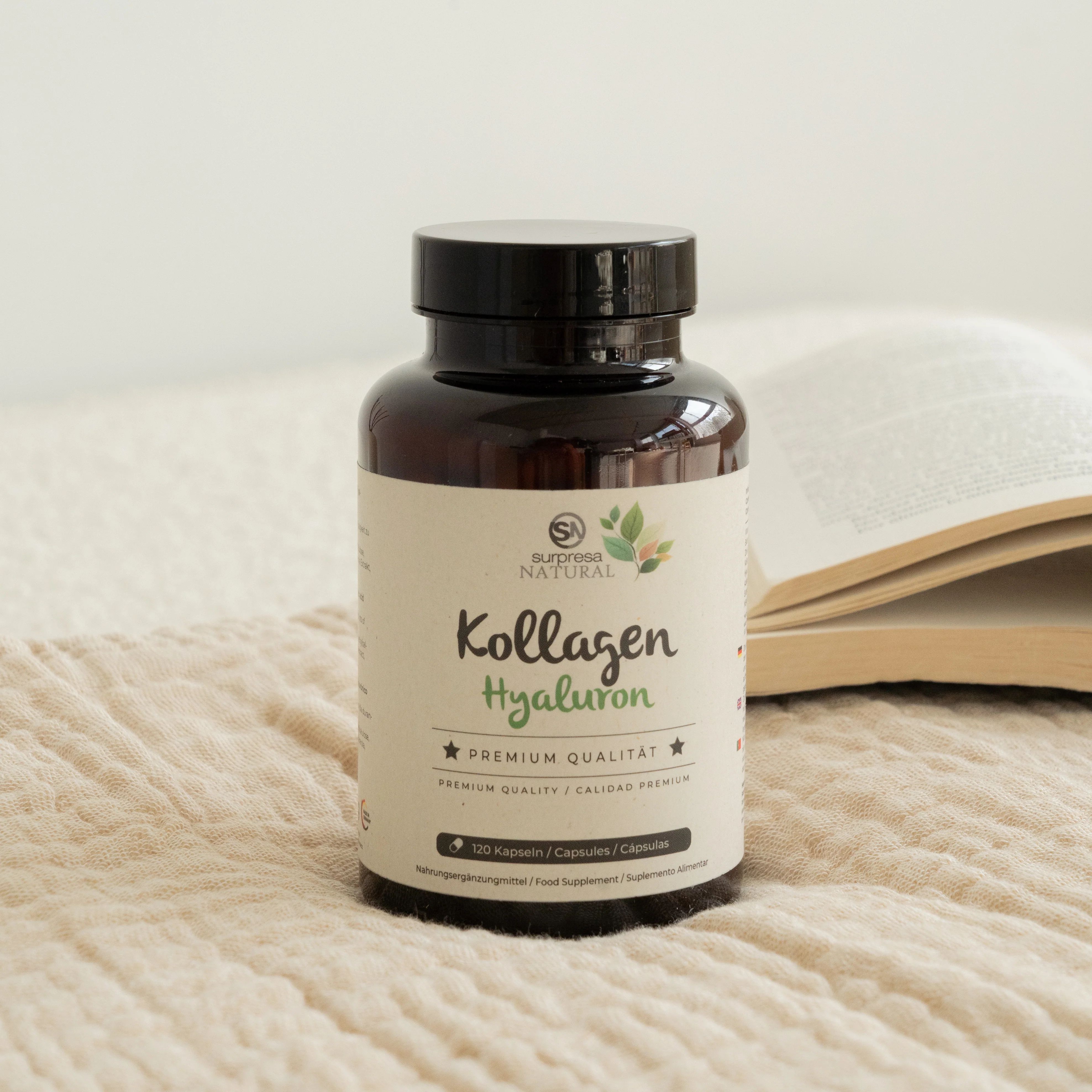 Braune Flasche mit Kapseln. Aufschrift: Surpresa Natural, Kollagen Hyaluron, Premium Qualität. 120 Kapseln. Buch im Hintergrund.