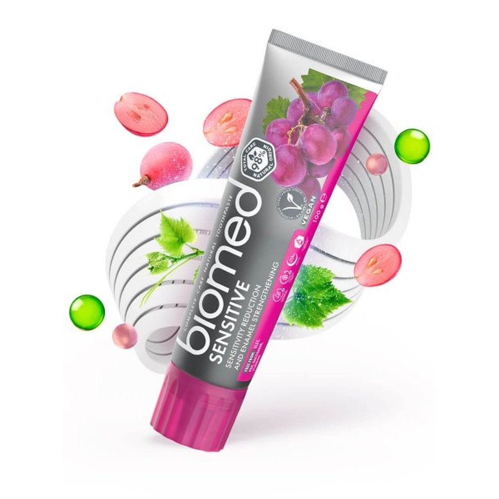 Zahnpasta-Tube "biomed Sensitive" mit Trauben und dekorativen Elementen. Vegan-Siegel und Qualitätszeichen.