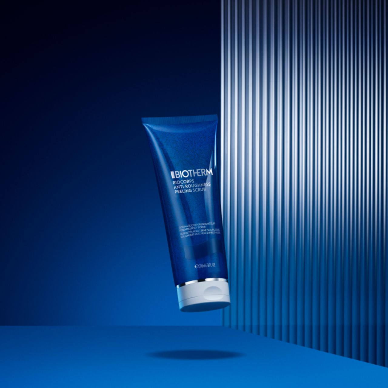 Blaue Tube mit weißem Verschluss vor blauem Hintergrund. Aufschrift: Biotherm, Biocorps Anti-Roughness Peeling Scrub.