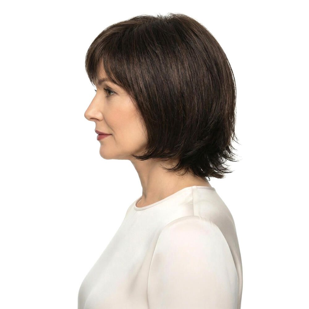 Braune Perücke mit Pony. Frau mit hellem Oberteil. Profilansicht.