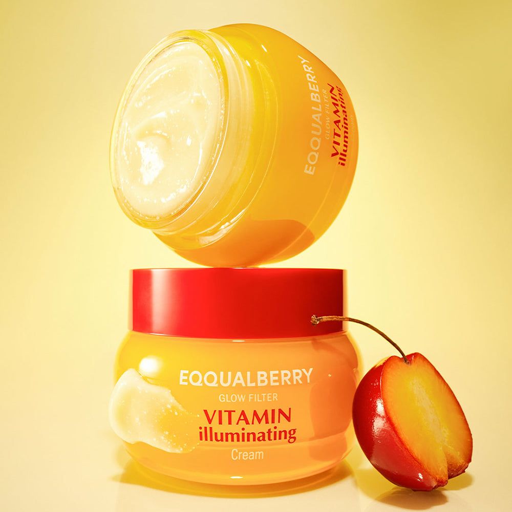 Zwei EQQUALBERRY Vitamin Illuminating Cream Tiegel, einer geöffnet. Eine halbe Frucht liegt daneben.