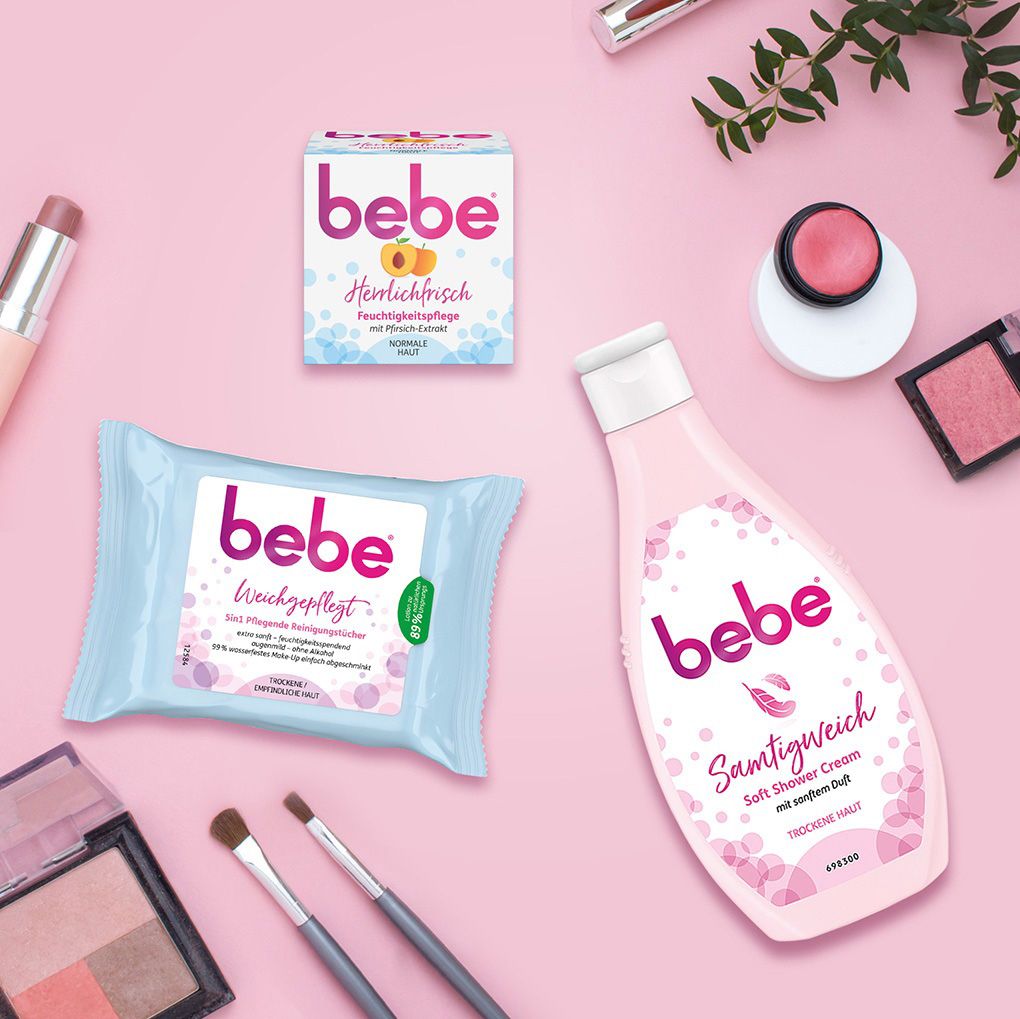 Bebe-Produkte: Feuchtigkeitspflege, Reinigungstücher und Soft Shower Cream. Auf rosa Hintergrund mit Make-up.