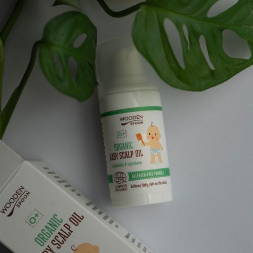 Flasche Wooden Spoon Bio-Babykopfhautöl neben Verpackung. Aufschrift: Organic Baby Scalp Oil, Cosmos Organic.