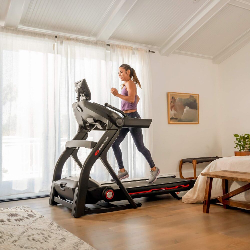 Frau läuft auf einem Laufband T25. Schwarzes Design. Konsole mit Bildschirm. Bowflex-Logo.
