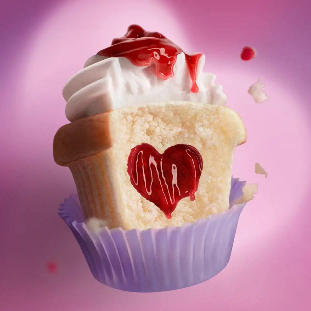 Cupcake mit Herz. Cupcake mit weißer Sahne und roter Soße. Herzförmiger Ausschnitt im Kuchen.