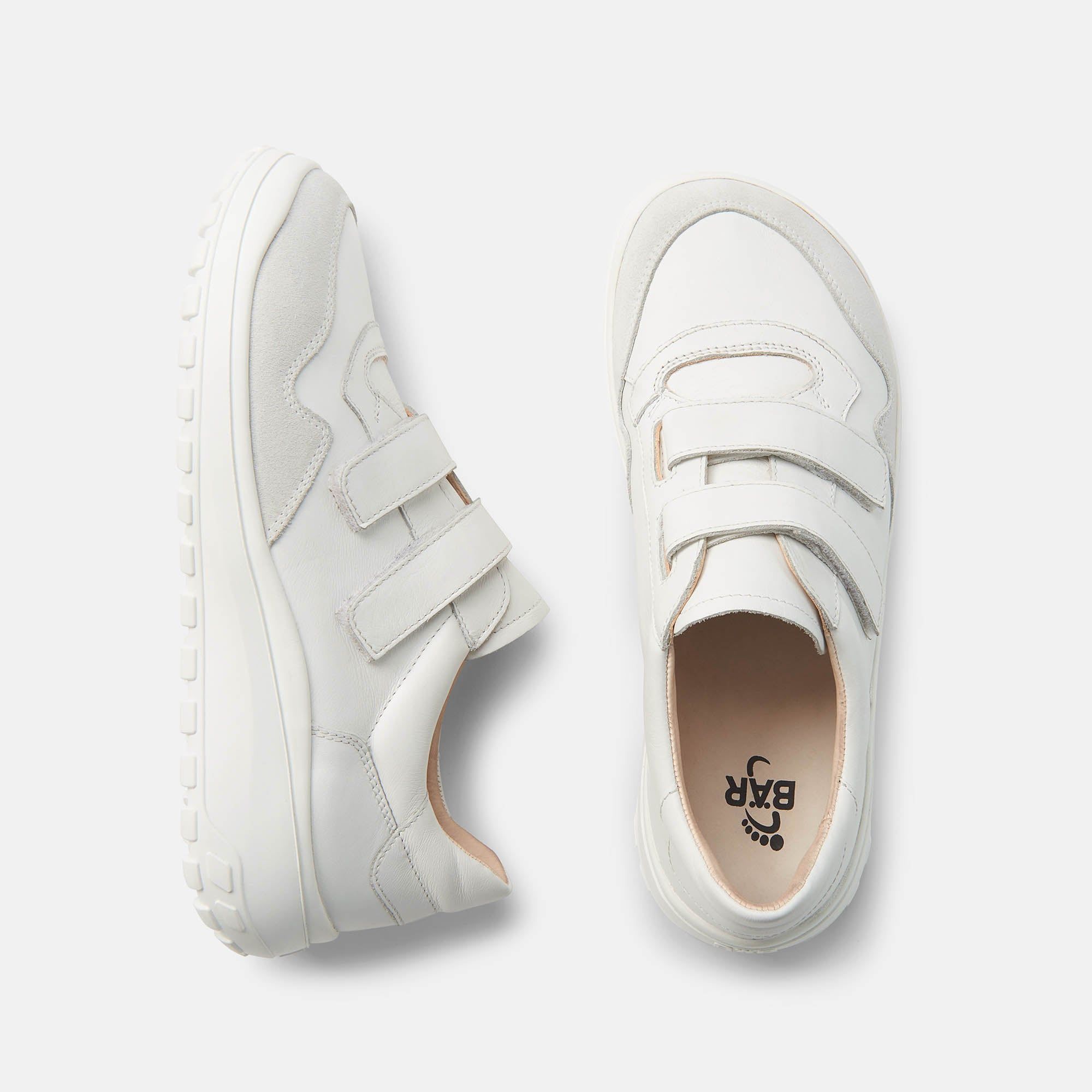 Draufsicht auf zwei weiße Herren-Slipper. Klettverschlüsse, graue Akzente. Auf einem Schuh steht BÄR. Breite Passform.