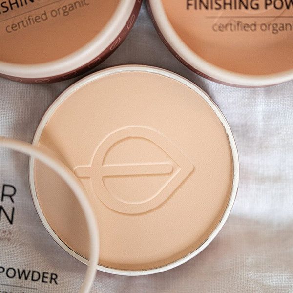 Drei runde Behälter mit hellem Puder. Sichtbar: Logo, Schriftzug Finishing Powder, certified organic.