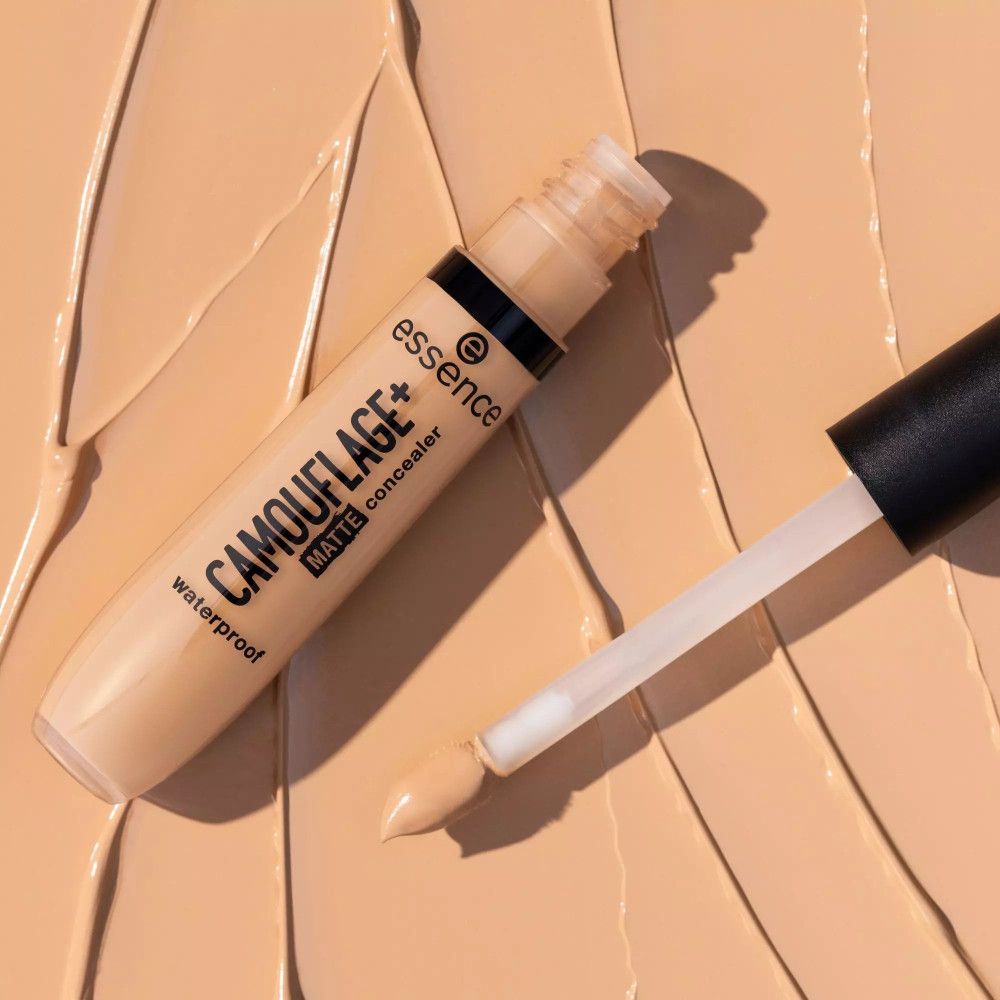 Concealer-Tube und Applikator auf beigem Hintergrund. Aufschrift: CAMOUFLAGE+ MATTE concealer waterproof. Marke: essence.