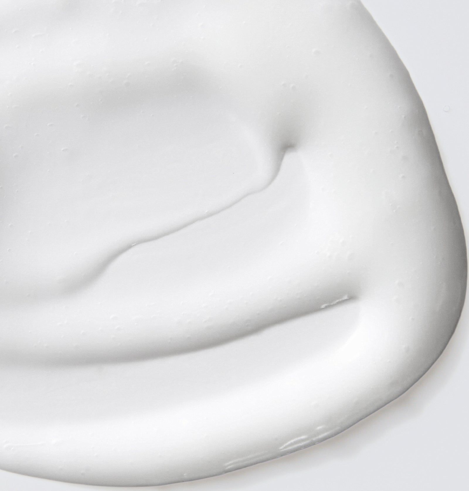 Nahaufnahme von weißem Serum. Glatte, cremige Textur. Wellenförmige Oberfläche.