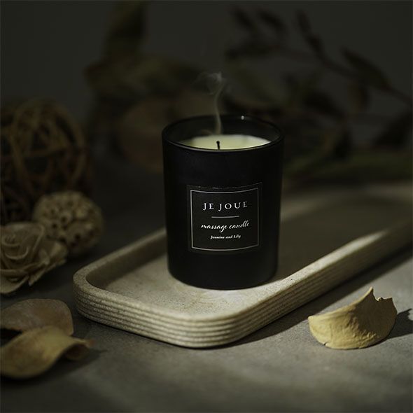 Schwarze Kerze mit Rauch. Aufschrift: JE JOUE, massage candle, Jasmine and Lily.