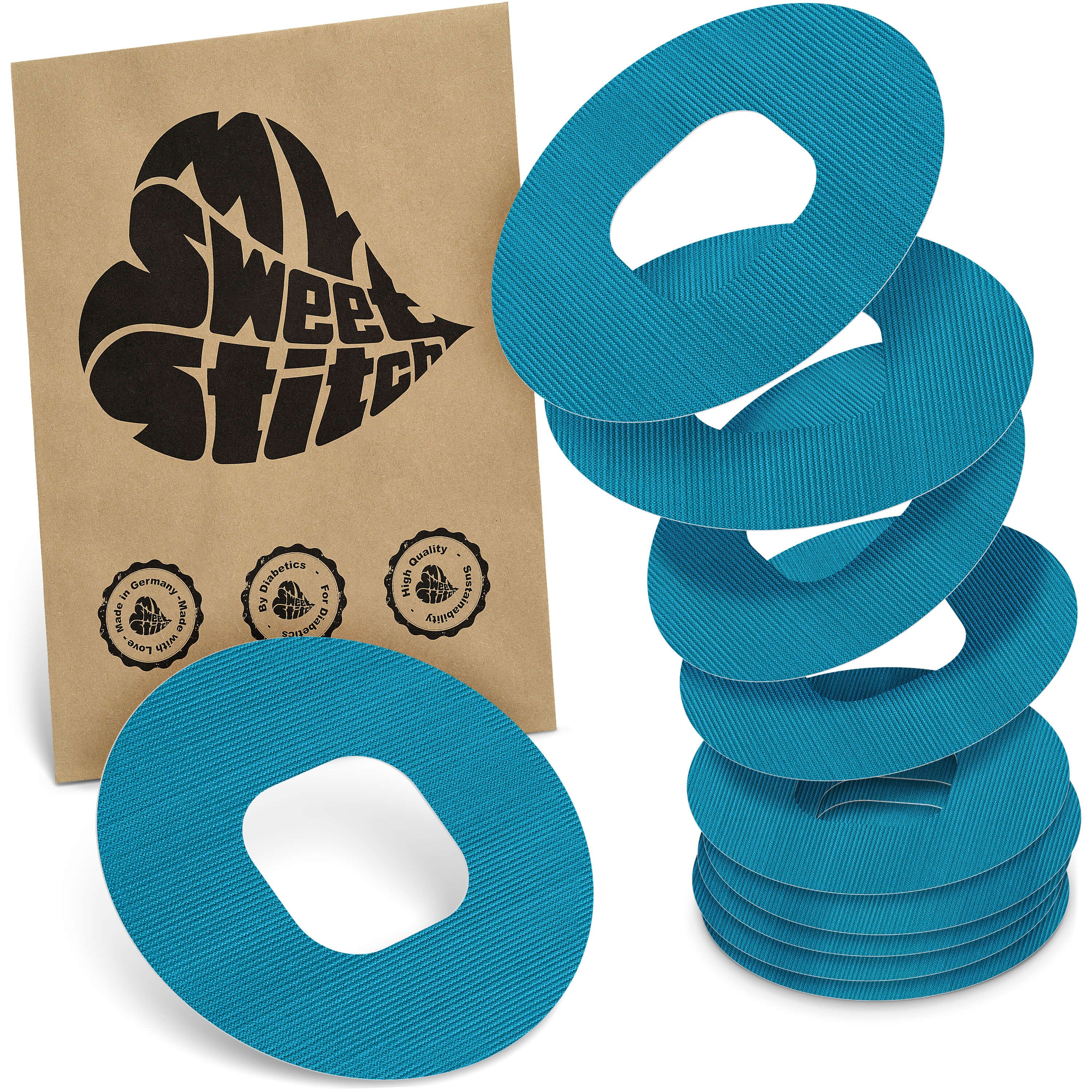 Türkisfarbene, ringförmige Pflaster mit ovaler Aussparung. Neben einer braunen Verpackung mit Logo und Qualitätssiegeln.