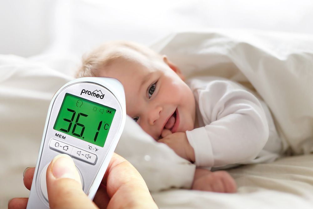 Thermometer misst Temperatur bei Baby. Anzeige: 36,1°C. Oben: "promed".