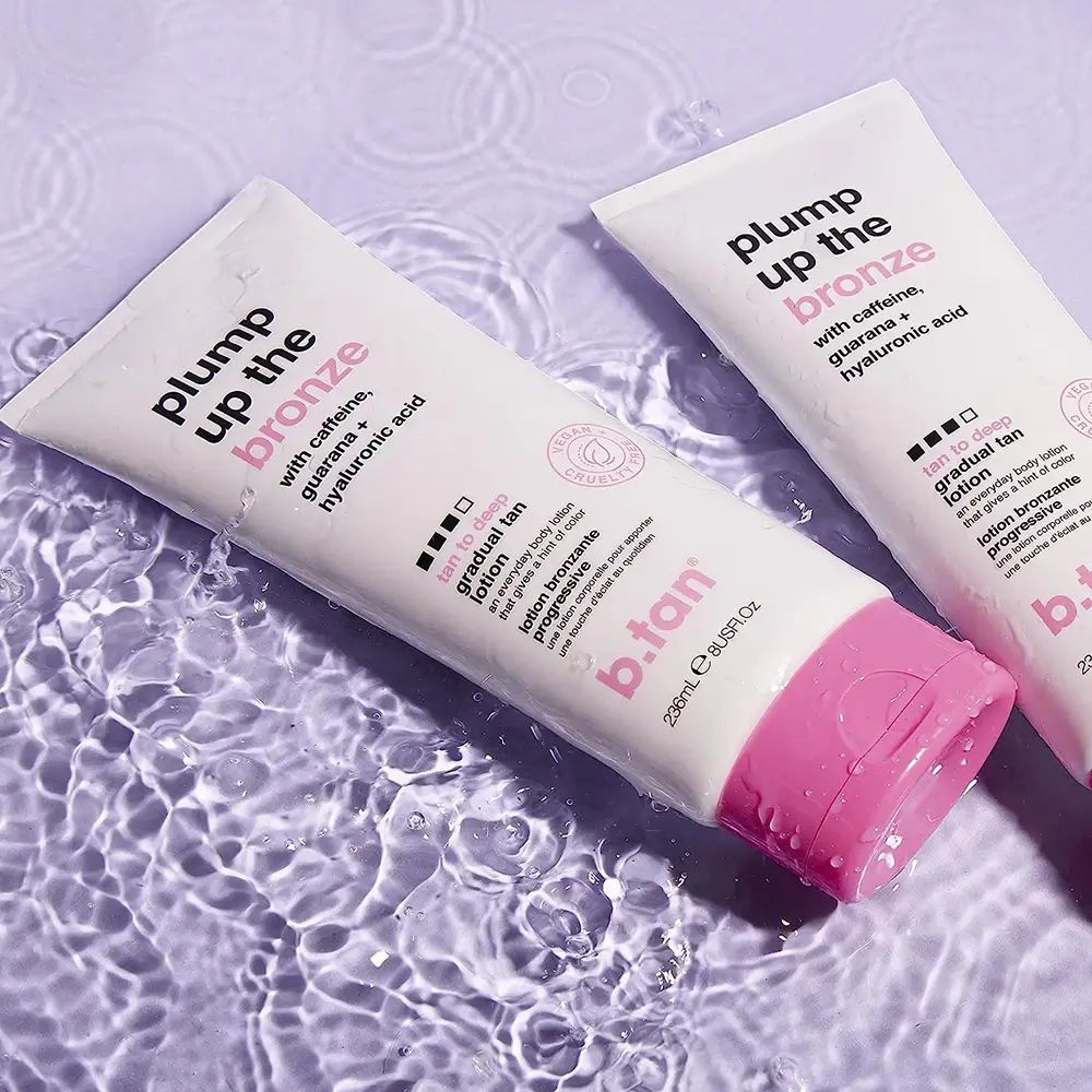Zwei weiße Tuben mit rosa Akzenten im Wasser. Aufschrift: Plump Up the Bronze, mit Koffein, Guarana und Hyaluronsäure.