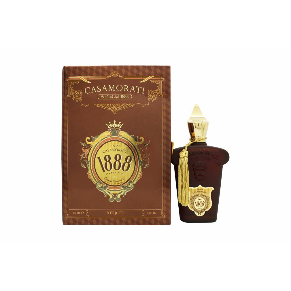 Braune Flasche mit goldener Kappe und Quaste, neben brauner Schachtel mit goldener Schrift und Logo.