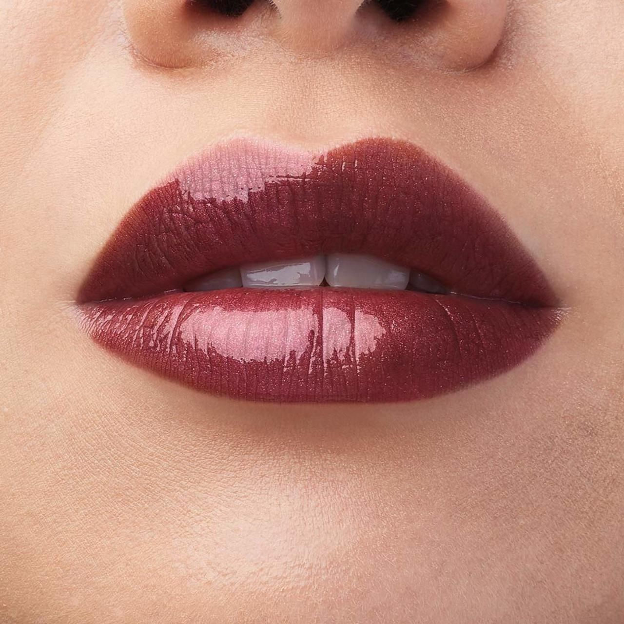 Nahaufnahme von Lippen mit rotbraunem Lippenlack. Glänzendes Finish. Deutlich sichtbare Lippenkonturen.