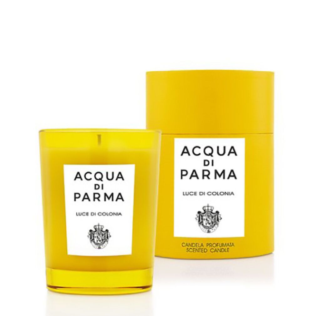 Gelbe Kerze in Glas, daneben zylindrische Verpackung. Beide mit weißem Etikett und Logo. Text: Acqua di Parma, Luce di Colonia.