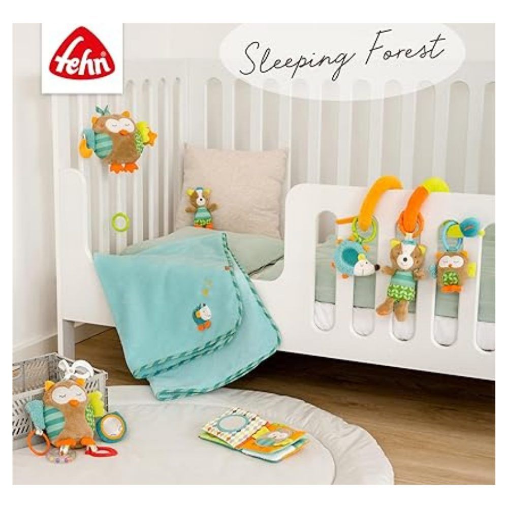 Babybett mit Textilien und Spielzeug. Stoffbücher, Eule-Mobile, Decke. Marke Fehn. Text: Sleeping Forest.