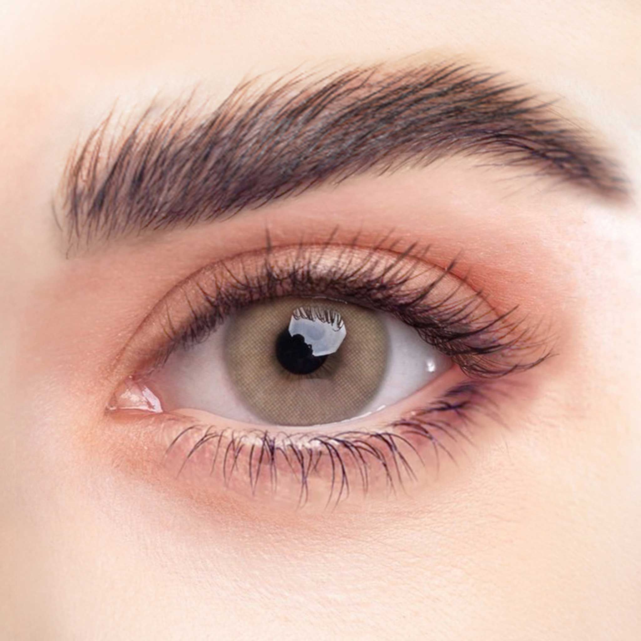 Nahaufnahme eines Auges mit BEIGEBRAUNEN Kontaktlinsen. Die Iris ist hellbraun. Lange Wimpern. Haut um das Auge.